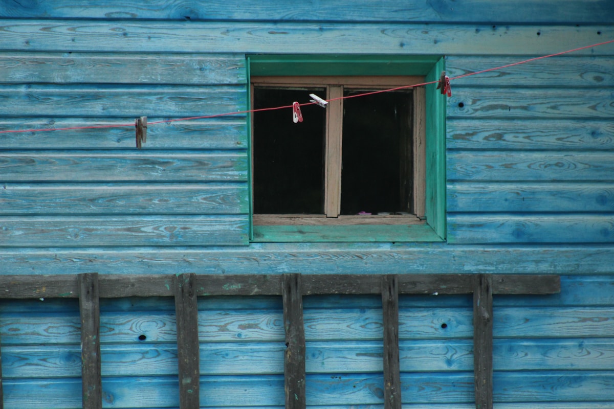 a blue building with a window and clothes line