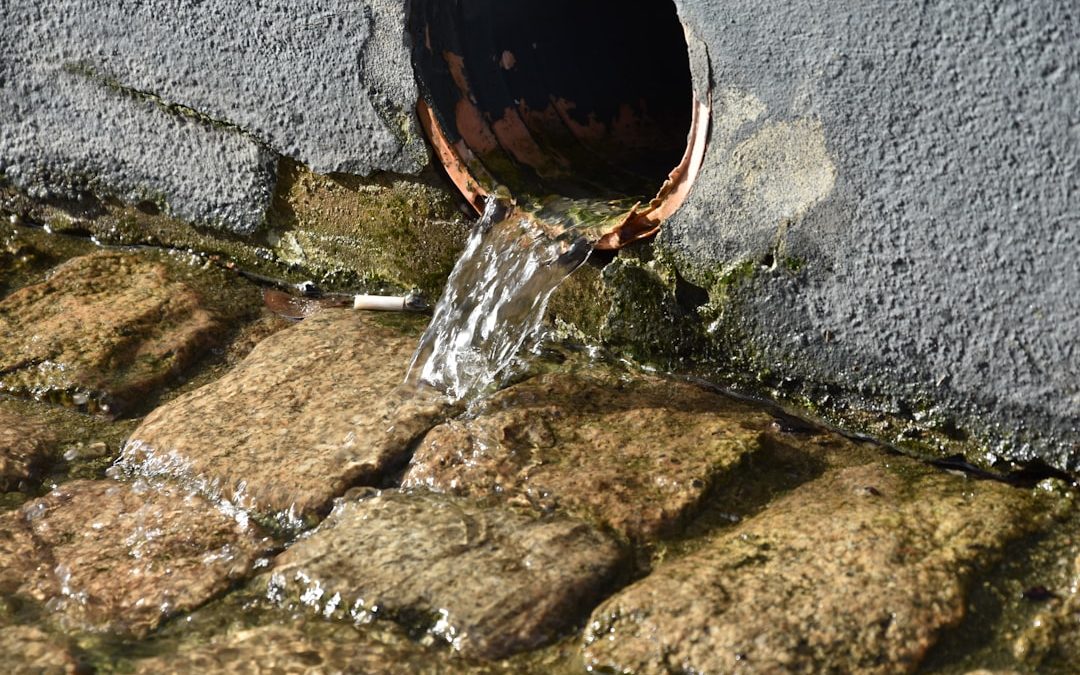 L'eau s'écoule d'un tuyau sur des pavés. Nos services de réparation de fuite d'eau invisible préviennent ces dégâts.
