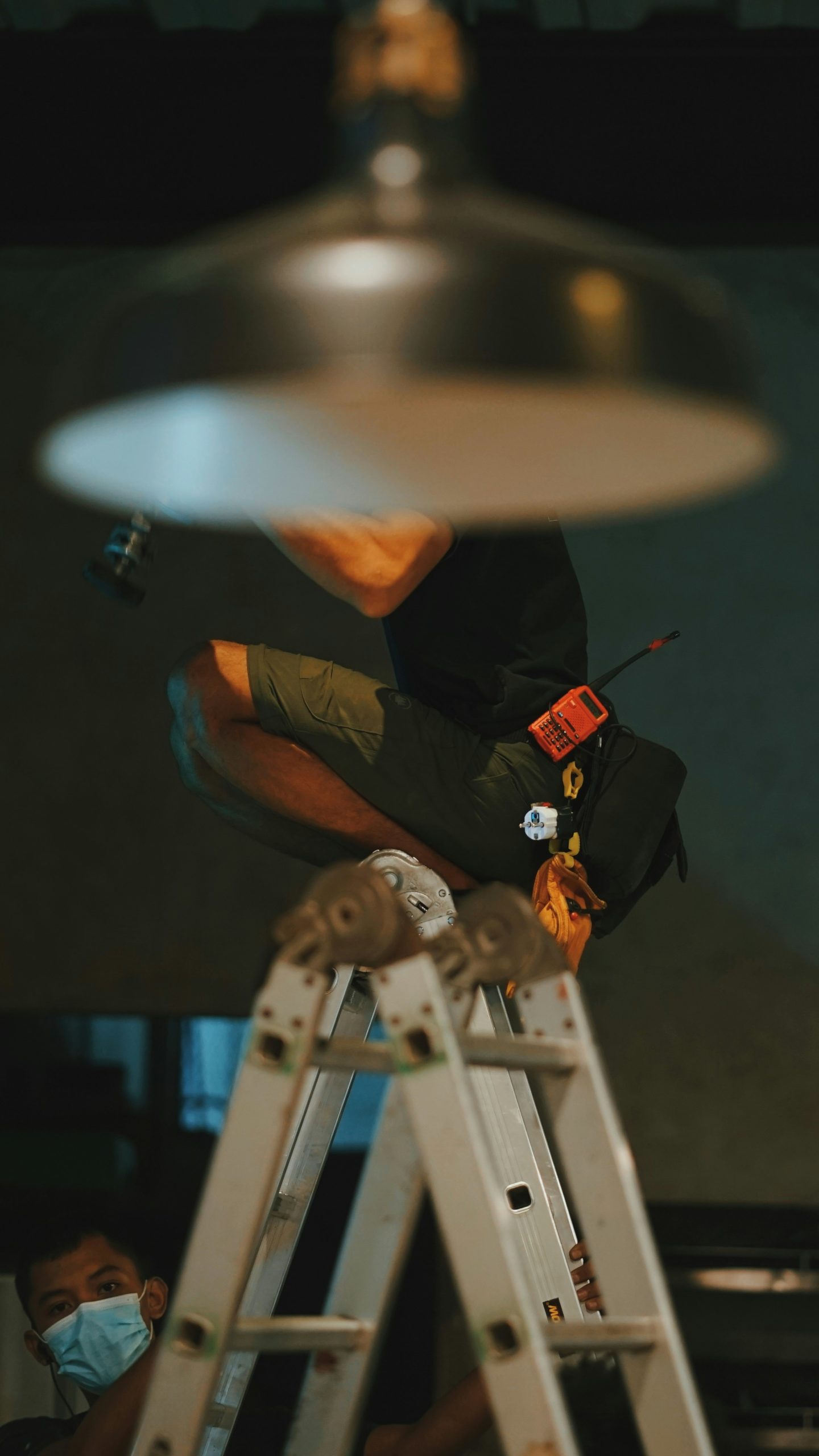 Plombier professionnel vérifiant les raccordements sous un évier avec une clé à molette, portant une tenue de travail sécurisée