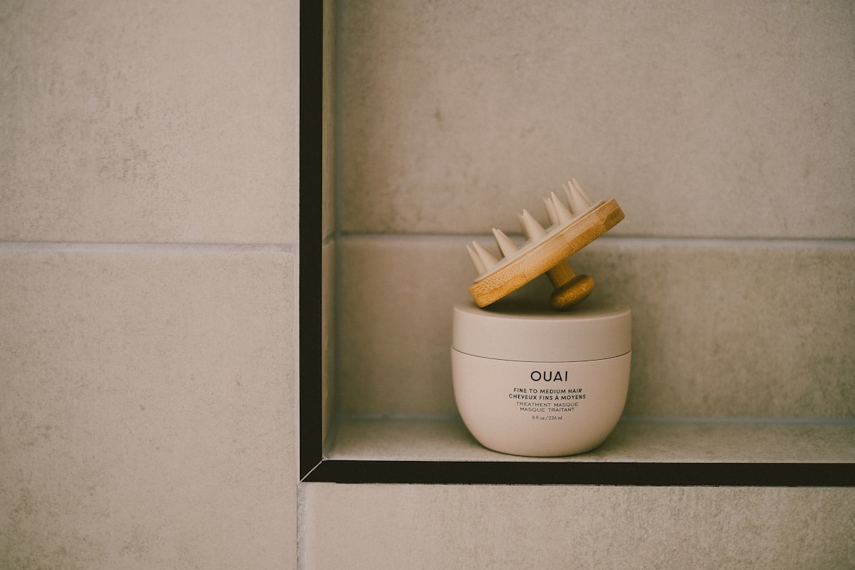 A skincare product and brush are on a shelf.