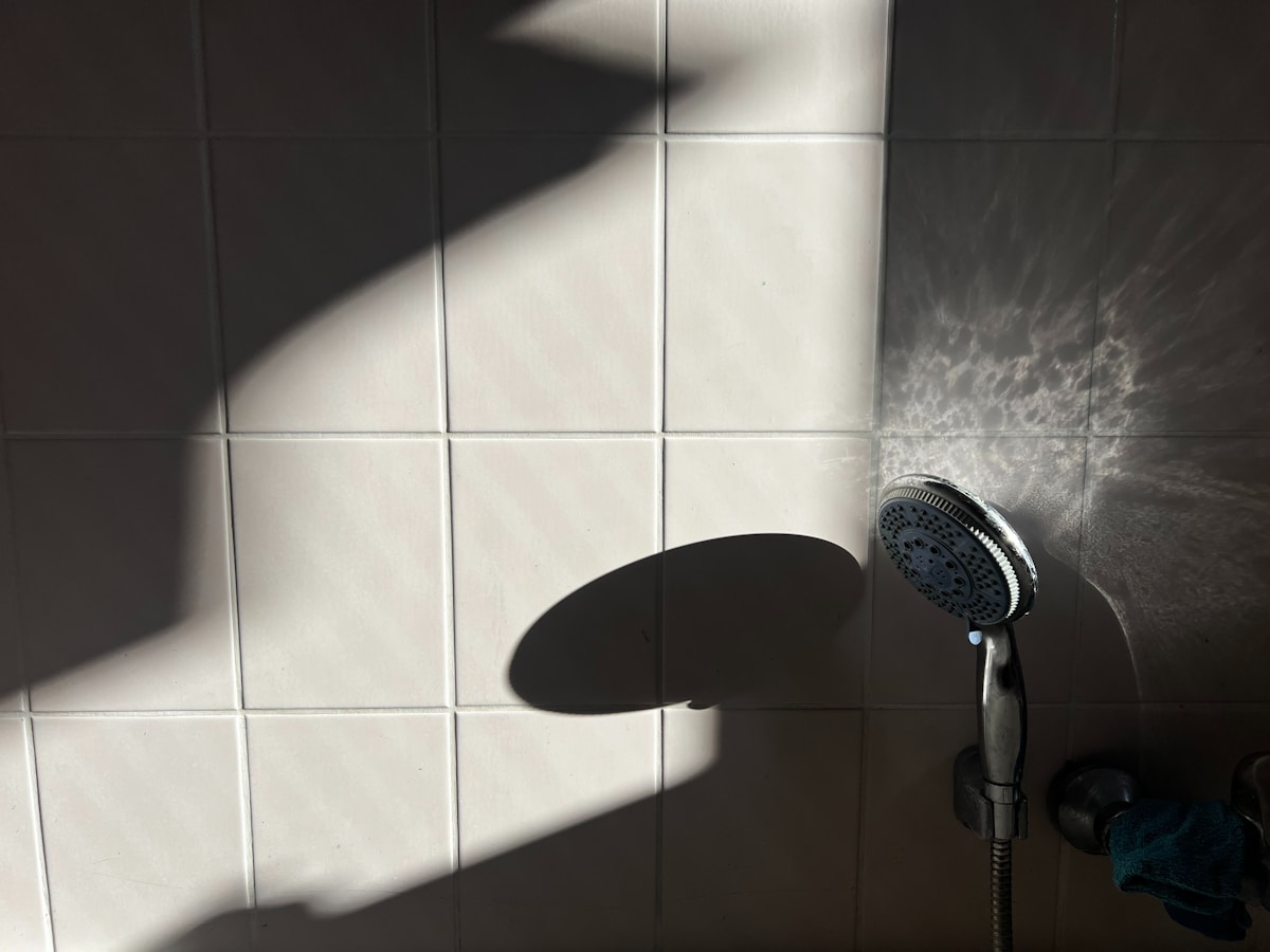 a shower head in a white tiled bathroom
