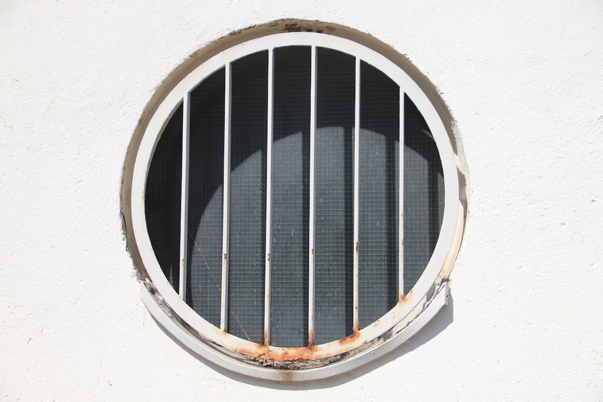 Round window with white bars on a white wall
