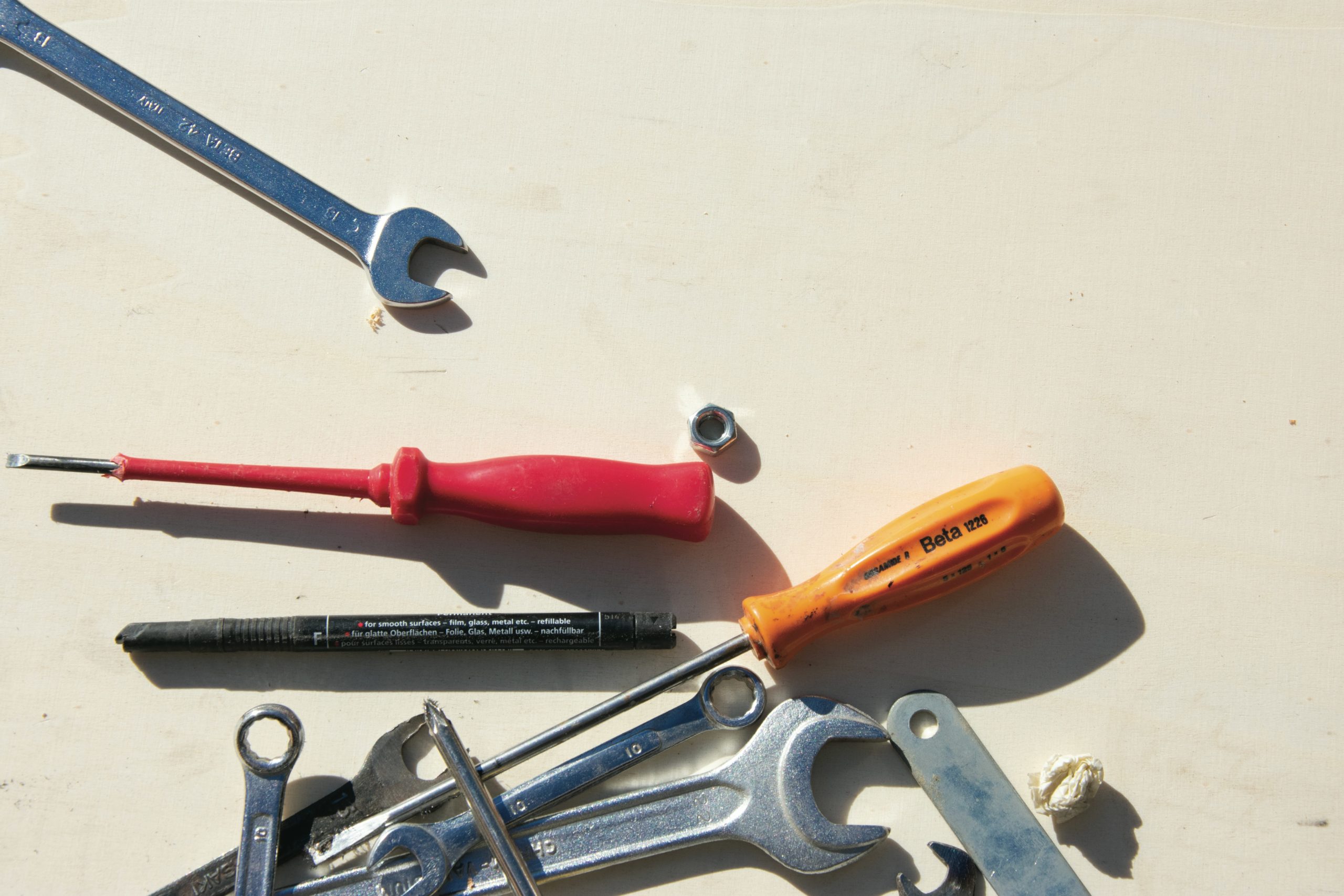 Assortiment d'outils de plomberie éparpillés sur un sol en bois, avec de lourdes clés et équipements spécialisés, suggérant la complexité.