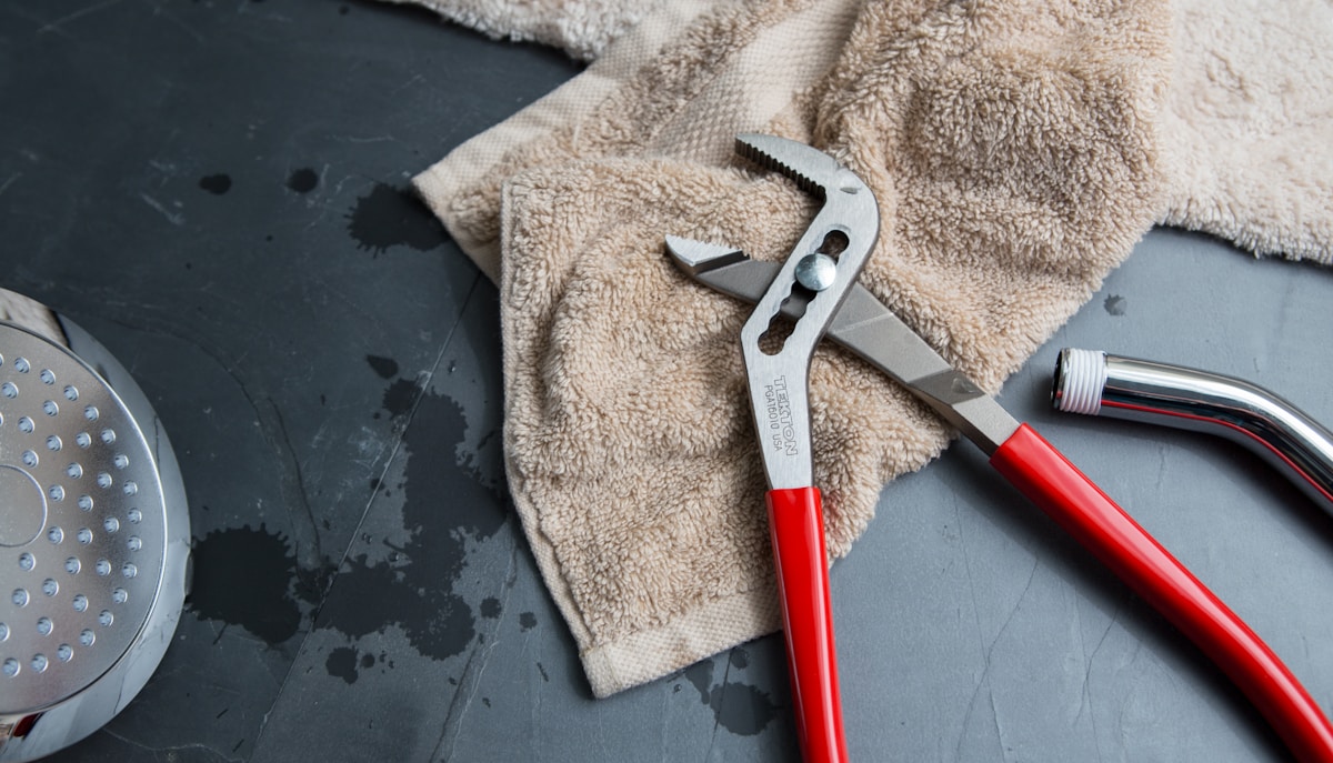 Outils de plomberie et serviette sur fond sombre.