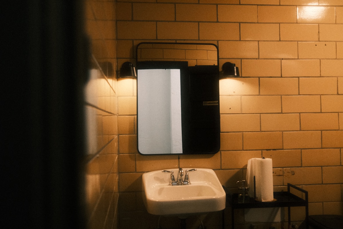 Lavabo et miroir dans une salle de bain sombre.
