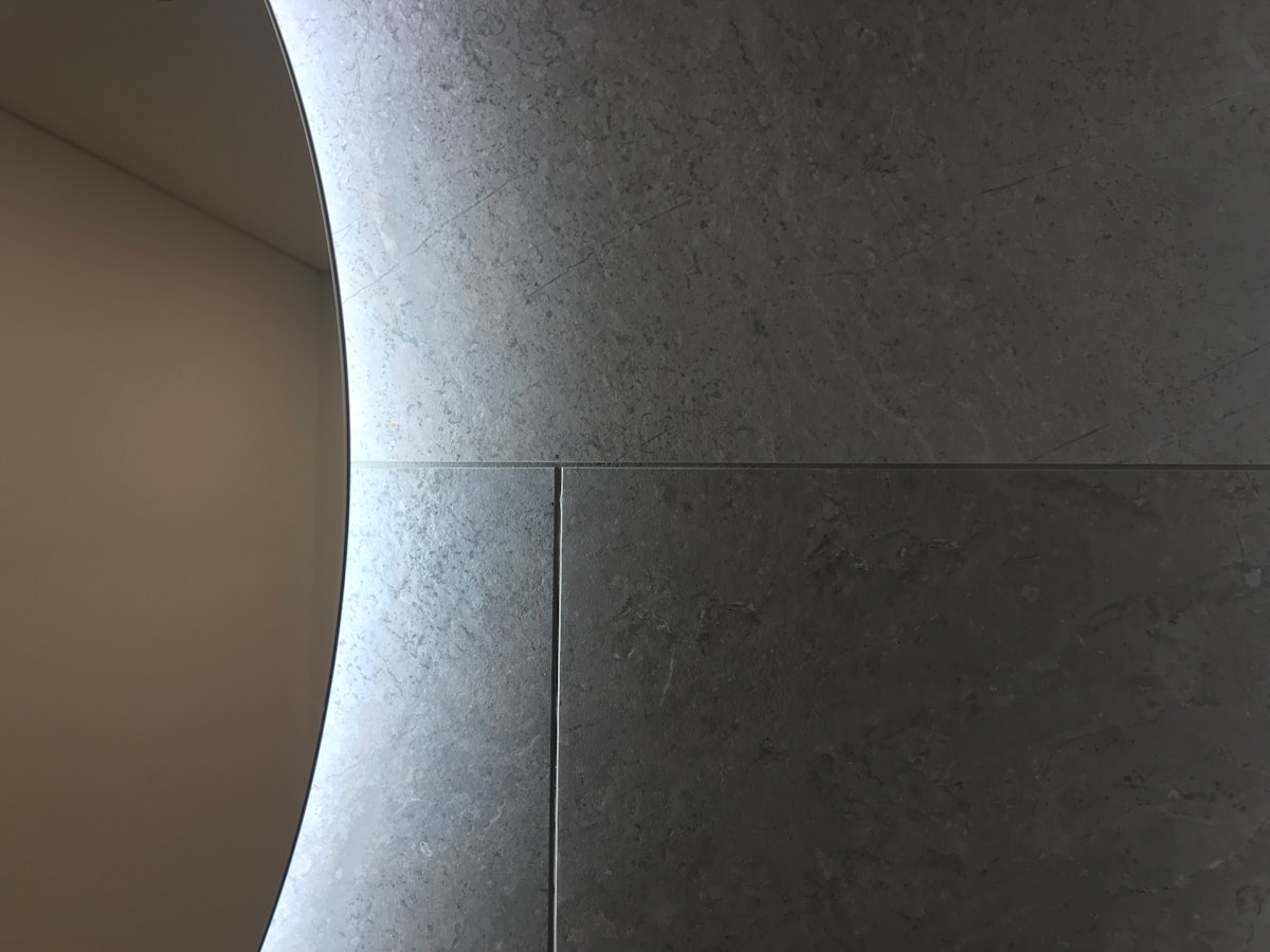 Miroir rond sur un mur de pierre grise.