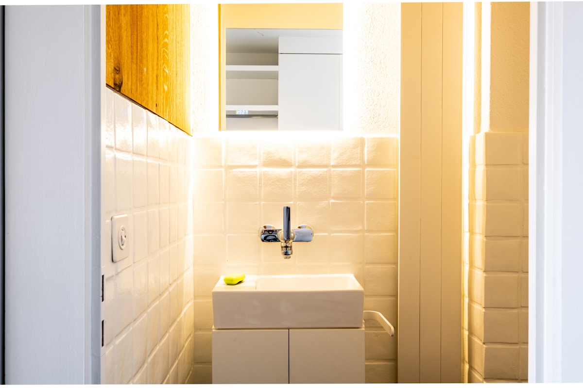 Salle de bain moderne avec carrelage beige et éclairage chaleureux.