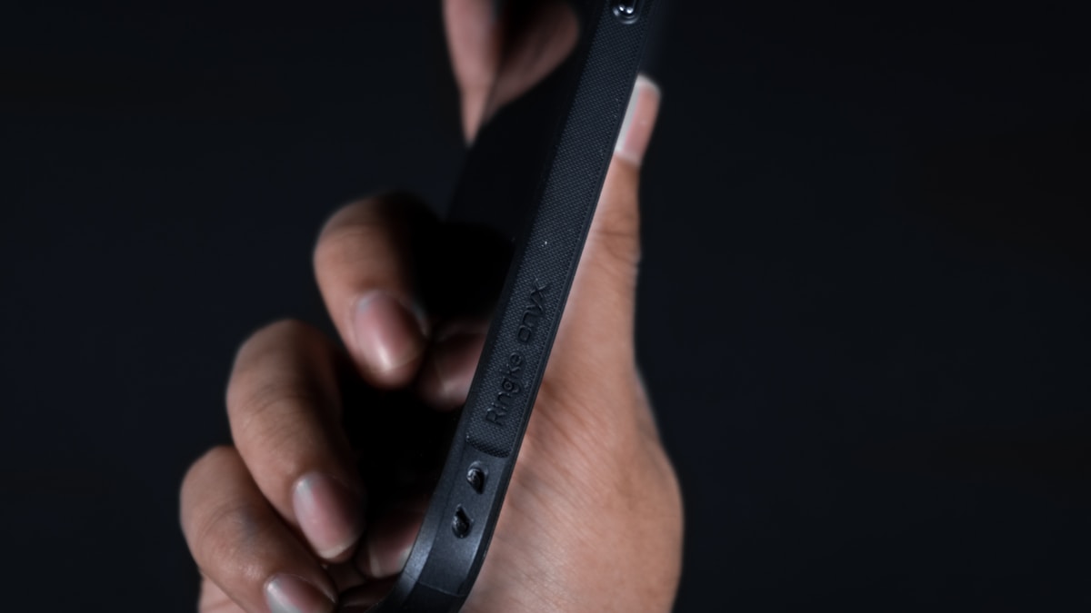 Gros plan sur un appareil électronique noir tenu dans la main.