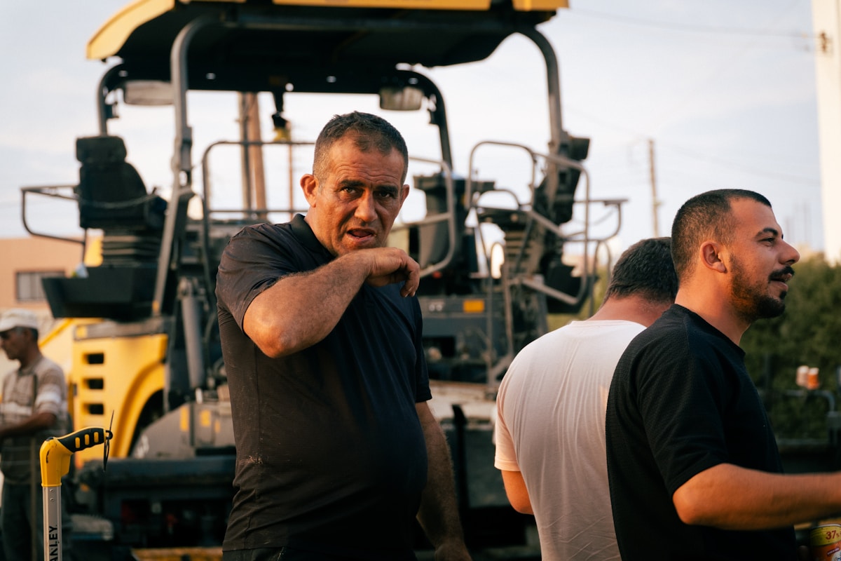Deux hommes en uniforme de travail près d'une machine de construction.