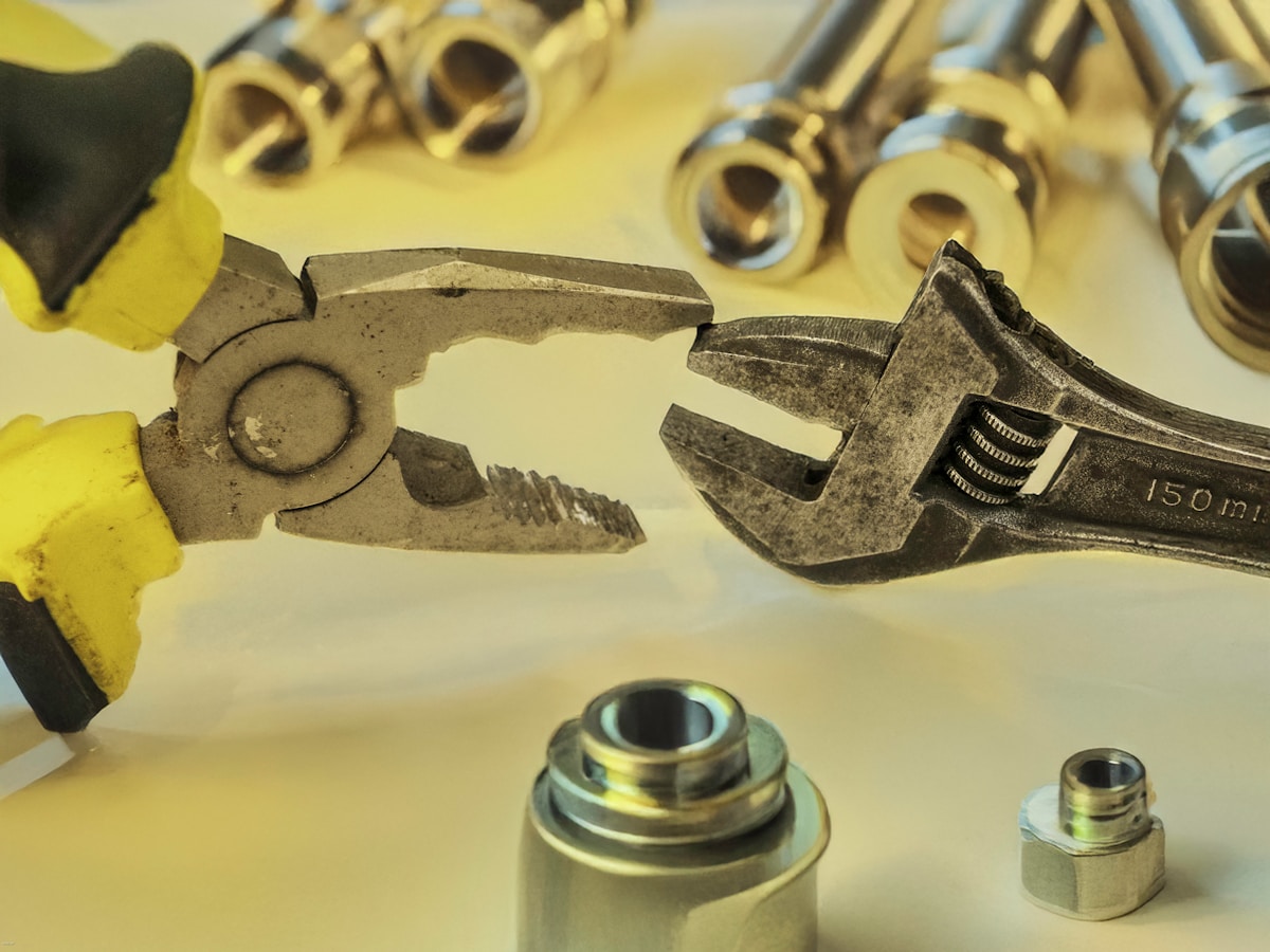 Outils de bricolage, pinces et clés de serrage sur fond jaune.