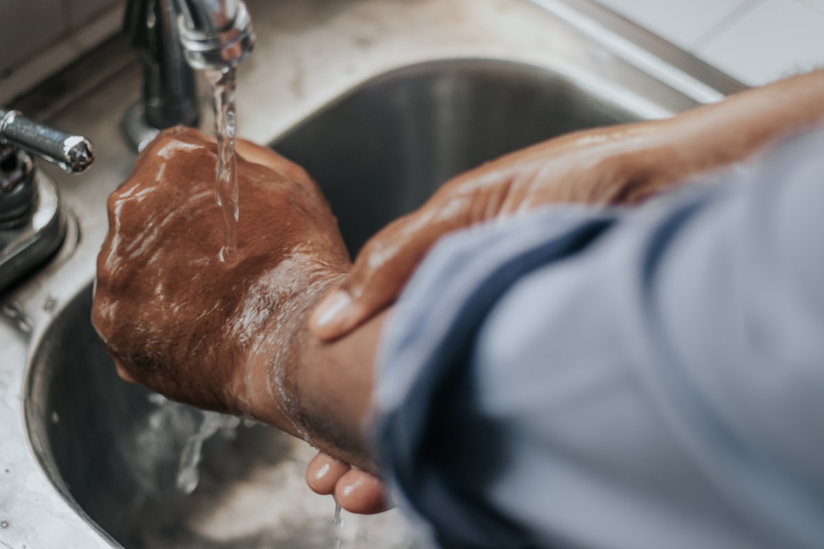 Mains lavées sous l'eau courante dans un évier.