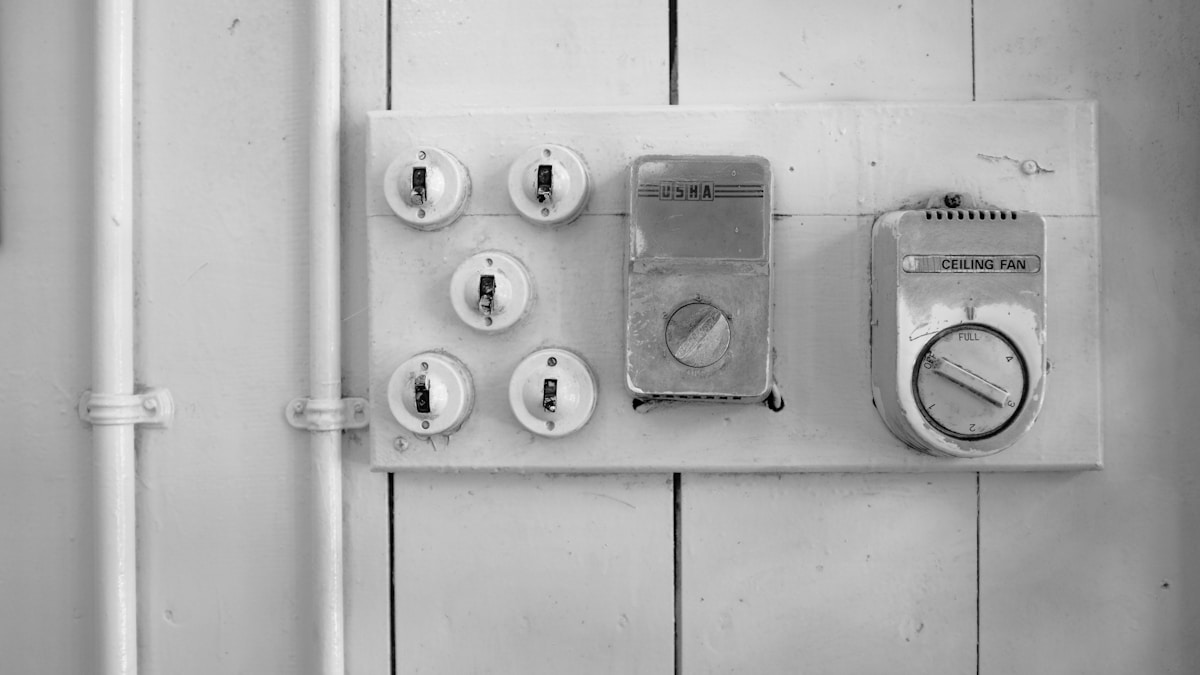 Tableau électrique vintage avec interrupteurs et ventilateur au plafond.