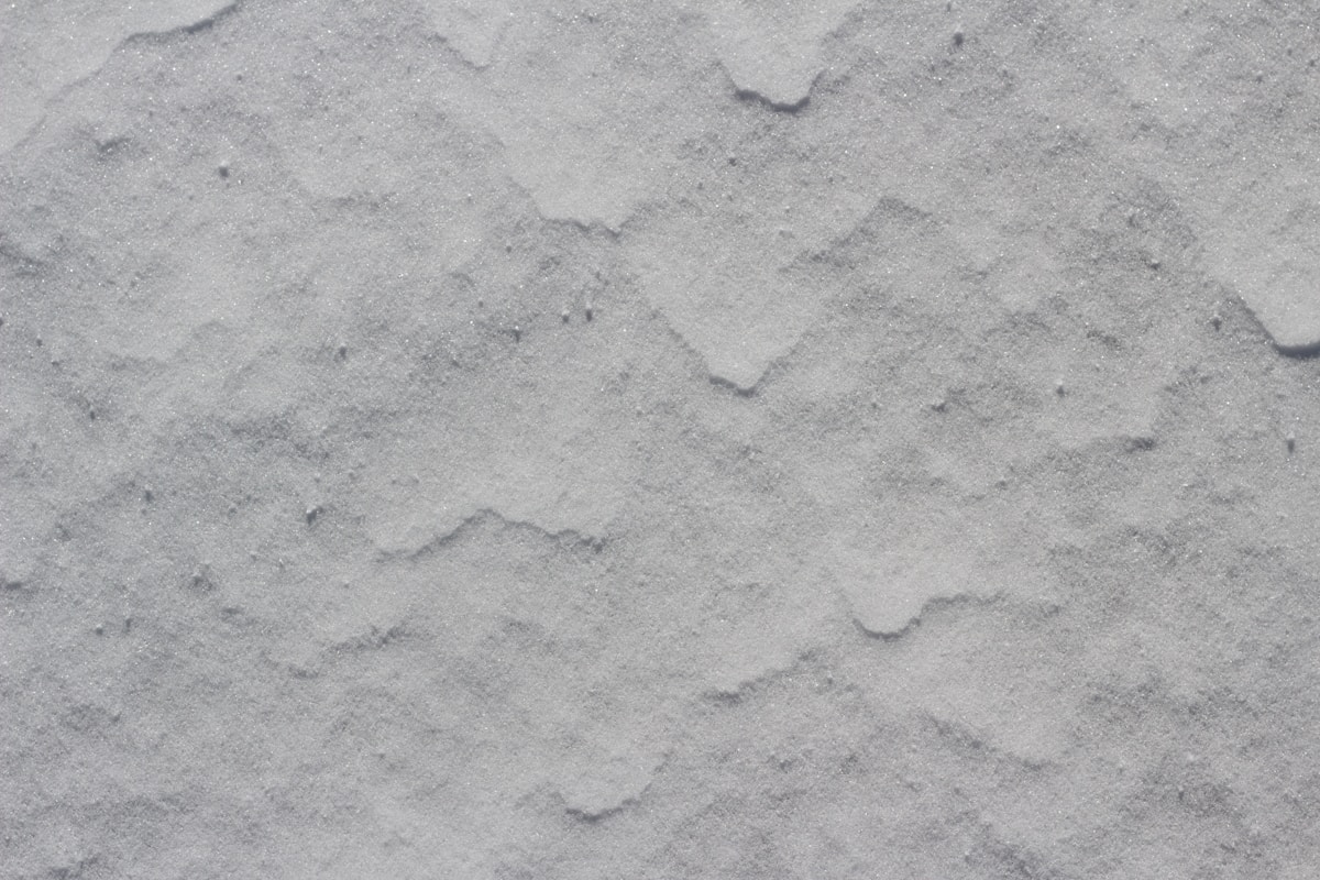 Texture de neige fraîchement tombée, surface granuleuse et irrégulière.
