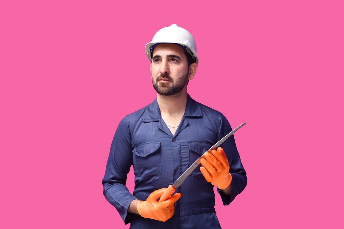 Ouvrier en uniforme bleu portant un casque de sécurité et des gants orange.