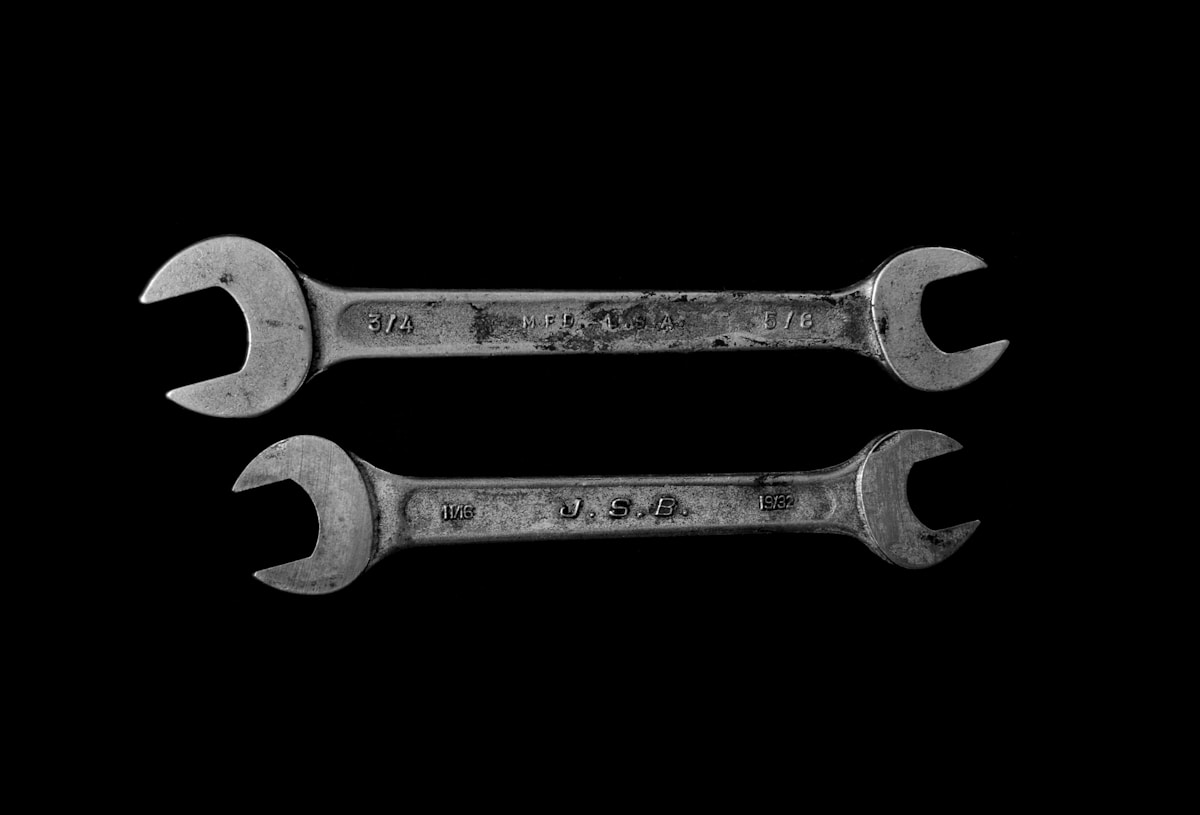 Deux clés de serrage métalliques usagées sur fond noir.