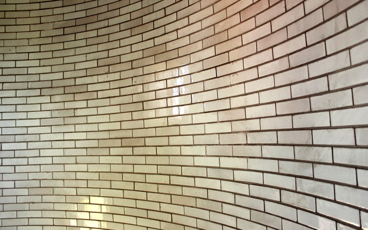 Mur de briques beiges avec motif ondulé.