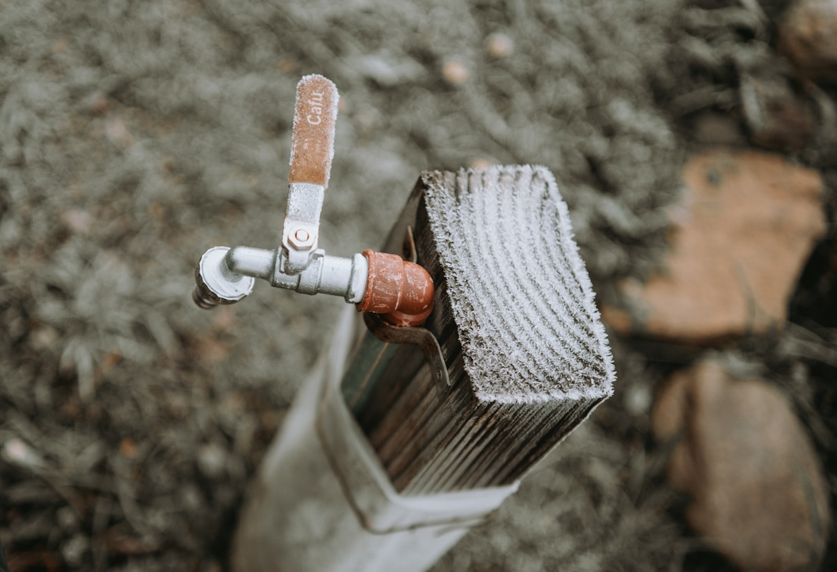 Robinet gelé avec brosse de nettoyage enneigée.