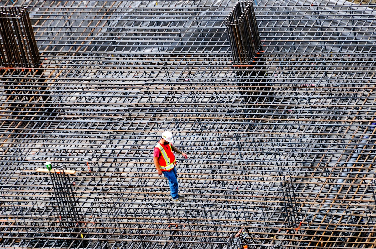 Travailleur sur un chantier de construction, entouré d'un échafaudage métallique.