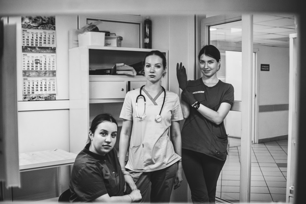 Trois femmes en uniforme médical dans un couloir d'hôpital.