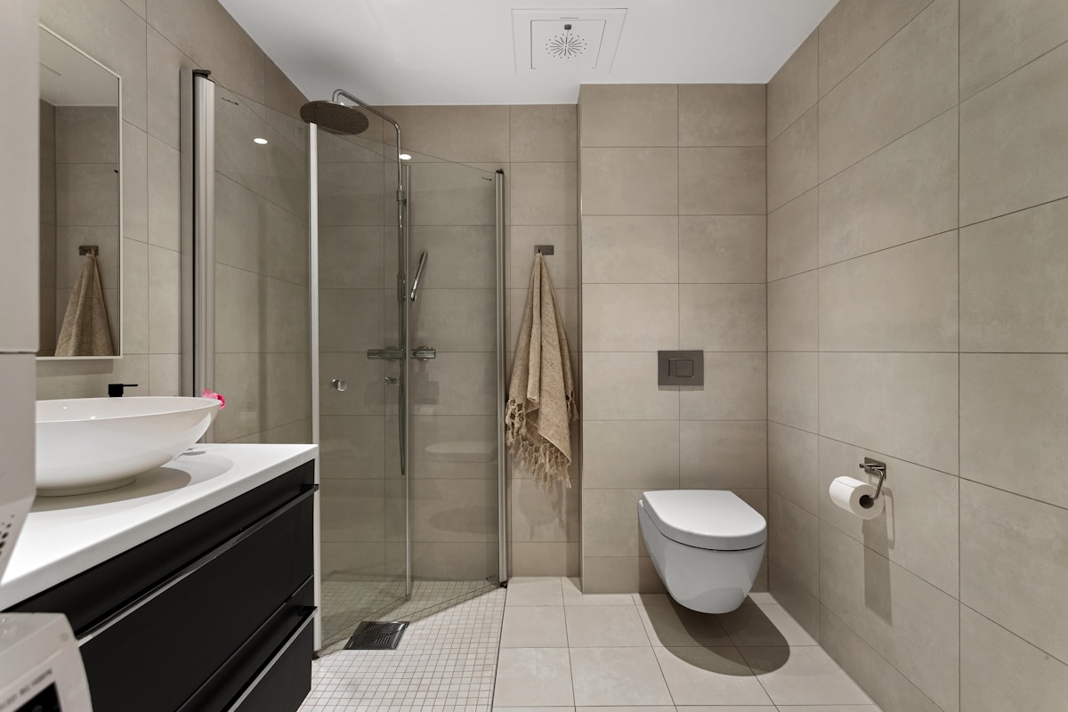 Salle de bain moderne avec douche, lavabo et toilette.