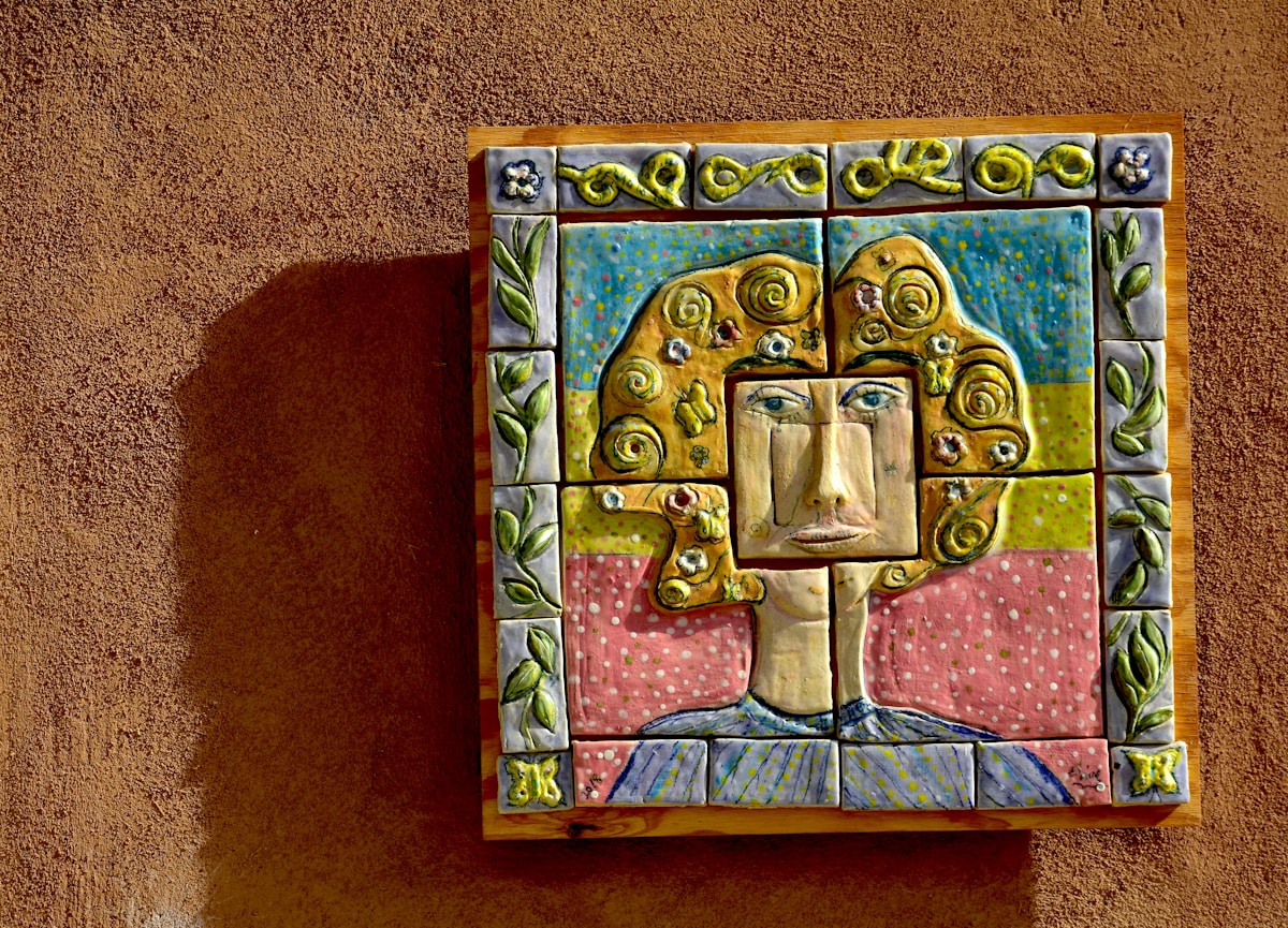Mosaïque colorée avec un visage stylisé et des motifs floraux.
