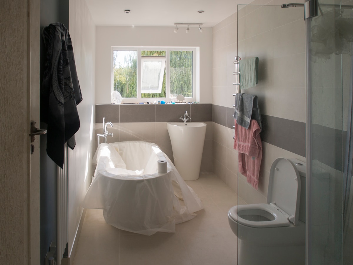 Salle de bain moderne avec baignoire, lavabo et fenêtre donnant sur l'extérieur.