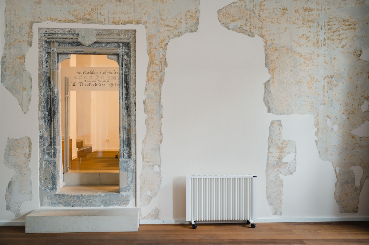 Porte en pierre avec inscription, radiateur blanc, mur décoré.