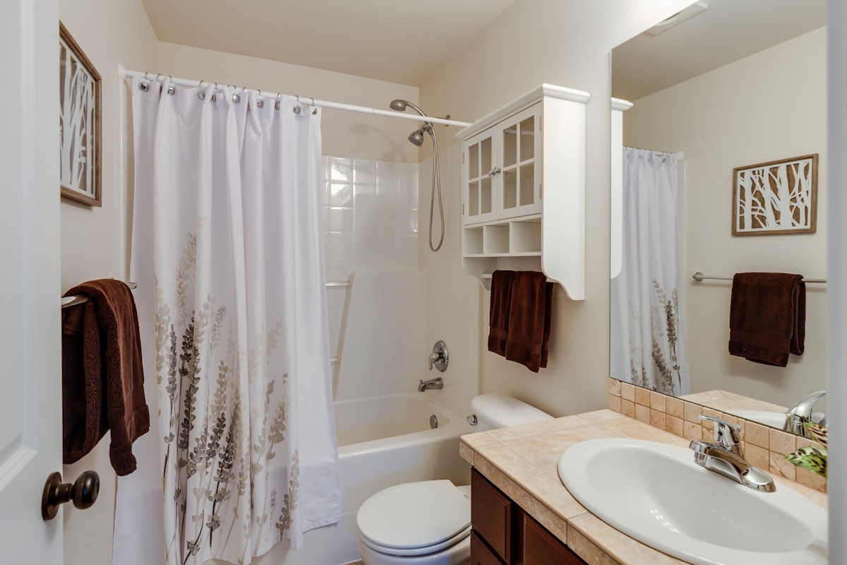 Salle de bain spacieuse et lumineuse avec douche, baignoire et meuble de rangement.