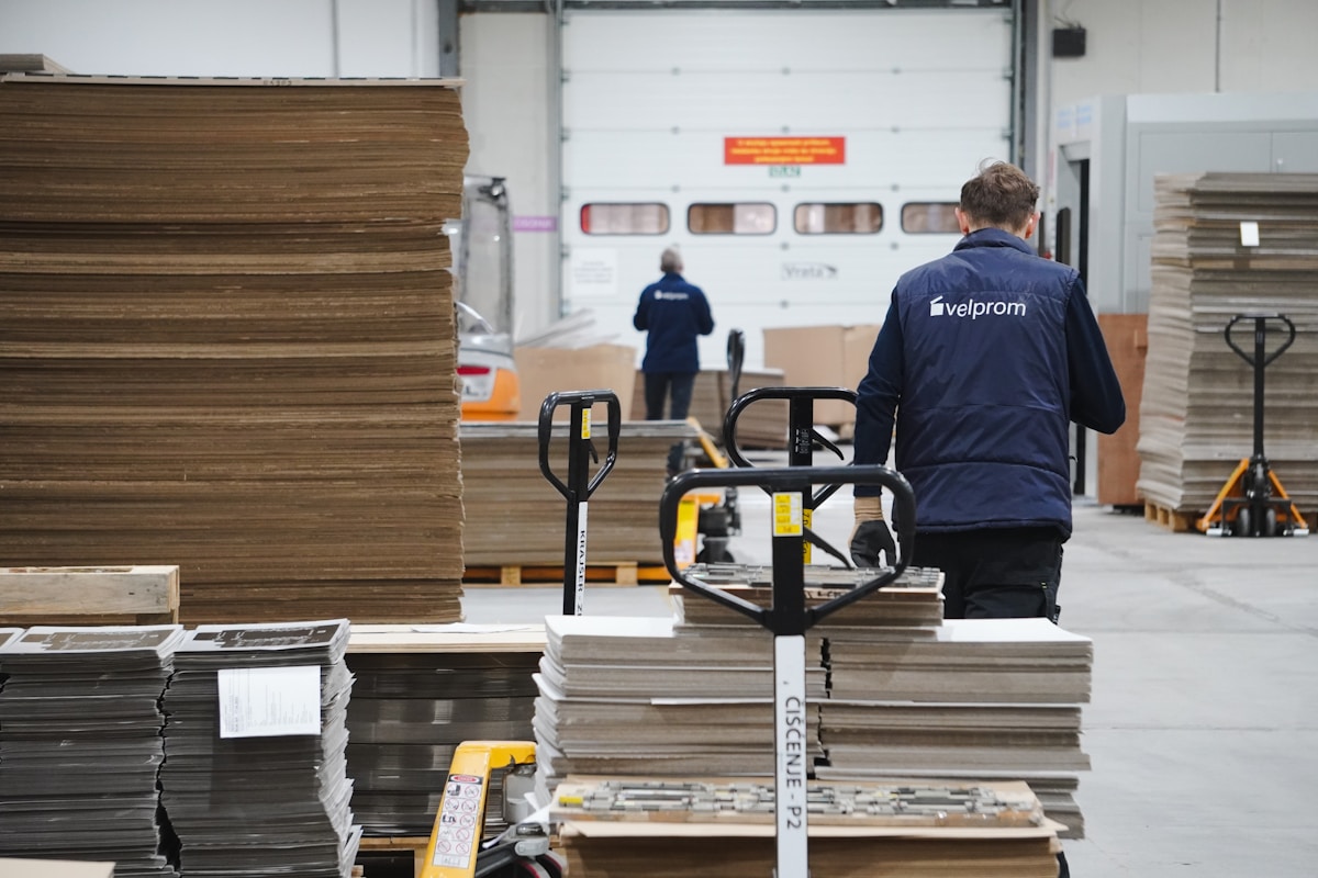 Entrepôt industriel avec des employés manipulant des palettes de carton.