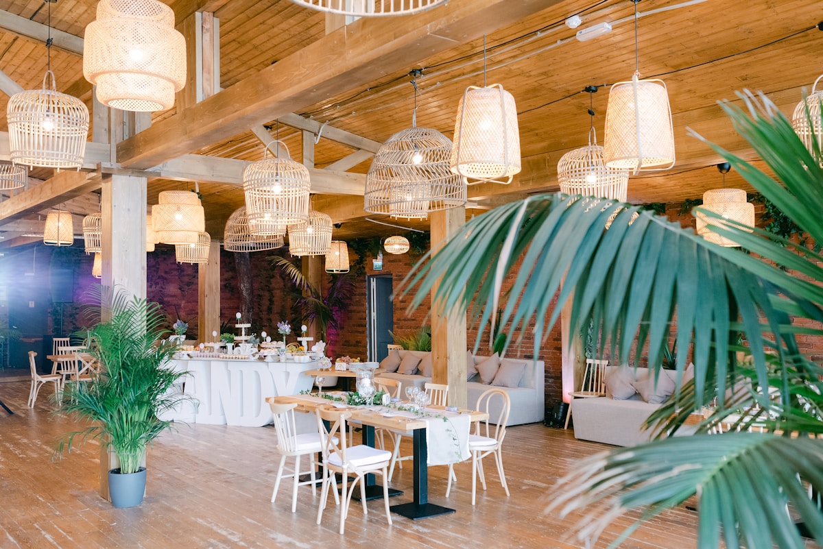 Salle de réception chaleureuse avec décoration tropicale, luminaires en rotin et mobilier en bois.