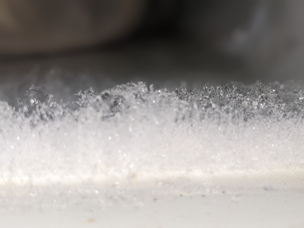 Texture cristalline de la neige avec des reflets scintillants.