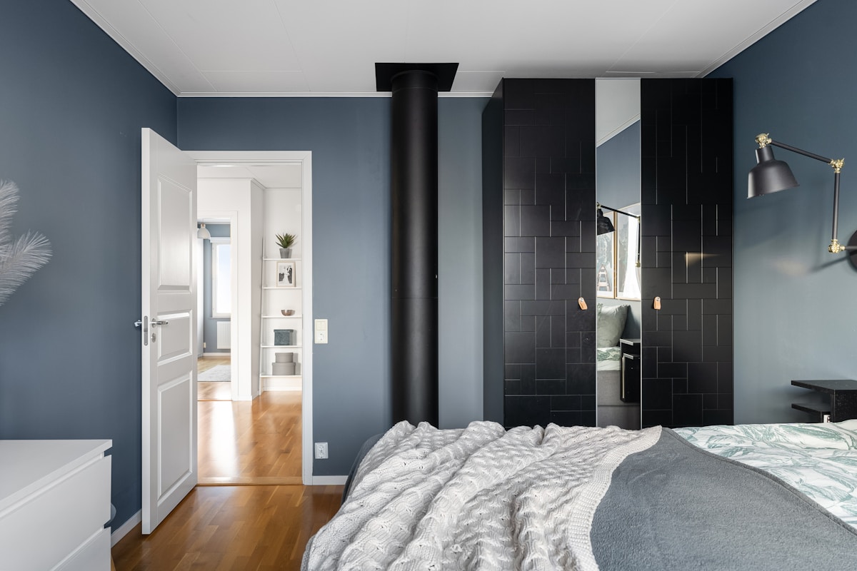 Chambre à coucher moderne avec murs gris foncé, mobilier noir et blanc.