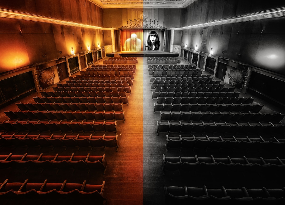 Théâtre abandonné, sièges rouges et noirs, scène avec portrait géant.