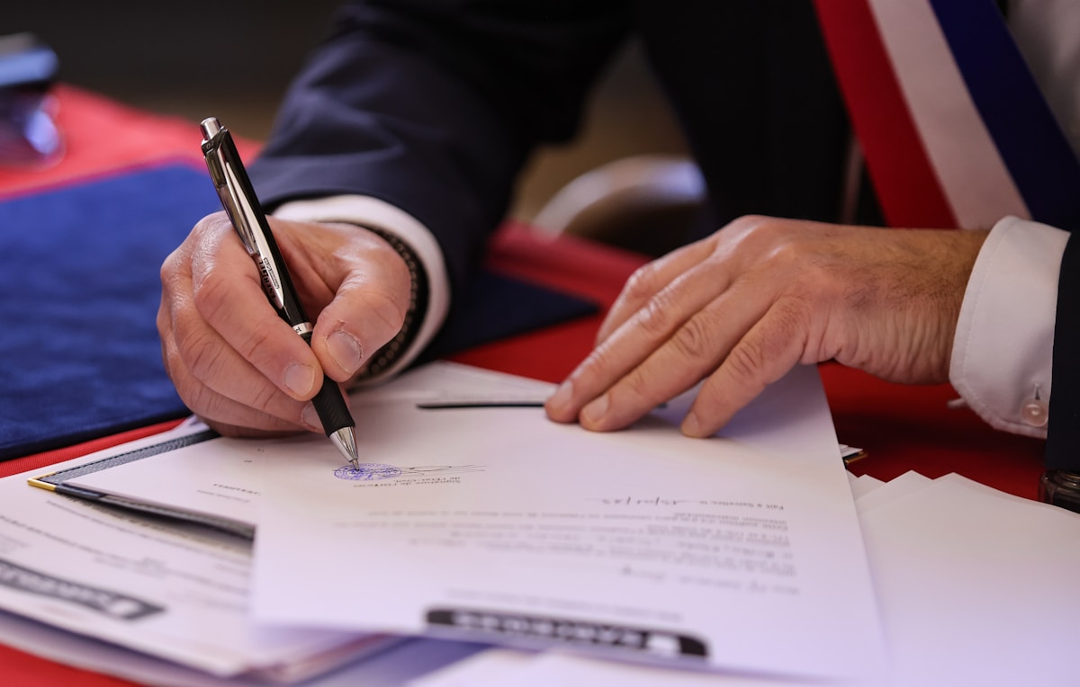 Mains d'un homme en costume signant un document officiel.