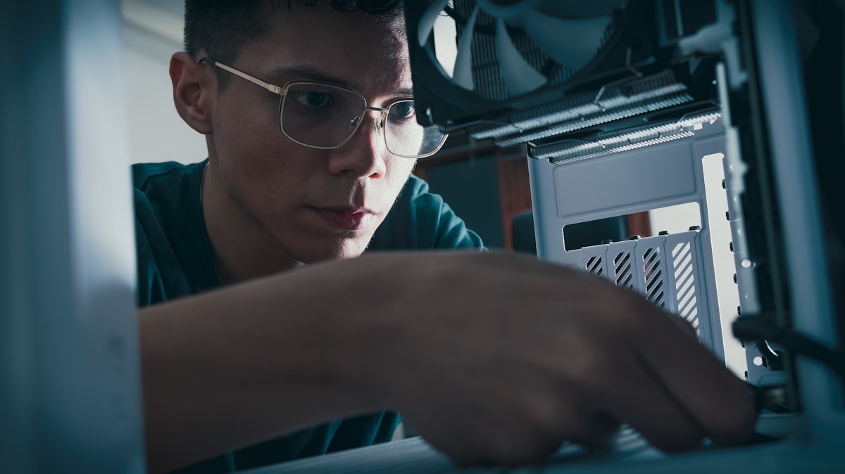 Jeune homme concentré réparant un ordinateur portable.