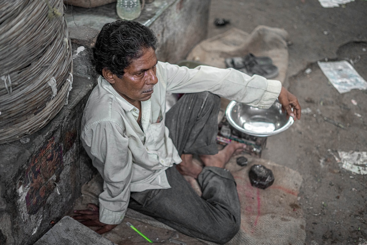 Homme âgé, assis, mangeant dans un bol, dans un environnement pauvre.