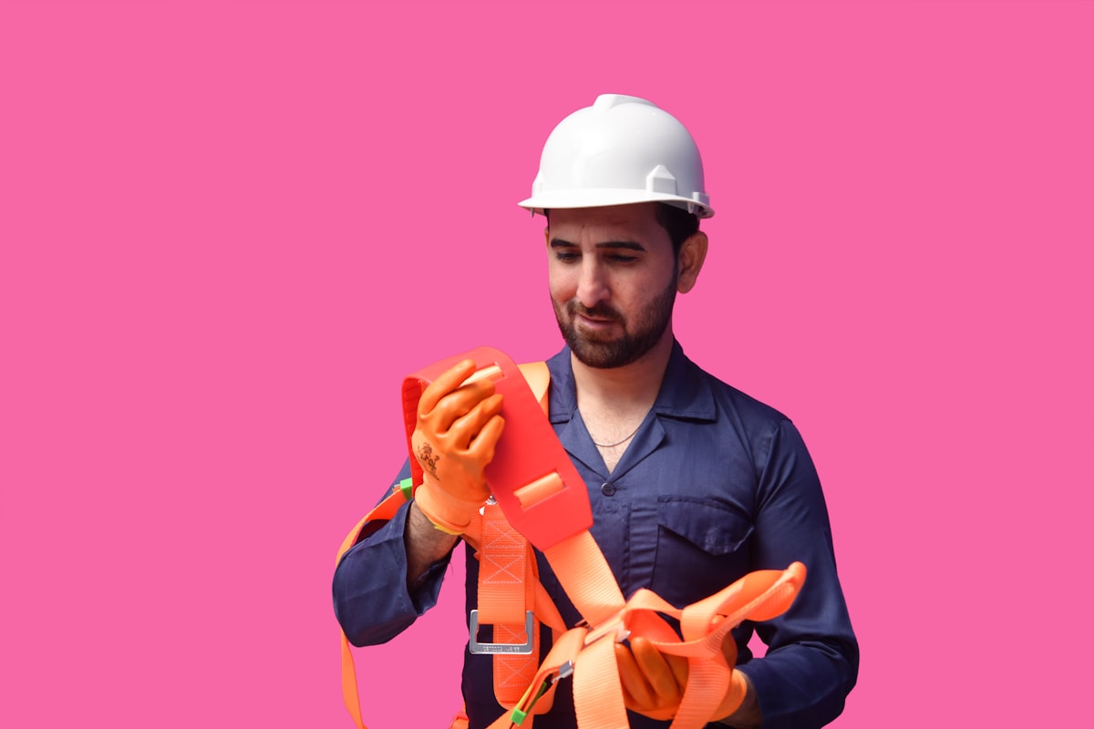Ouvrier en uniforme bleu portant un casque de sécurité et des gants orange.