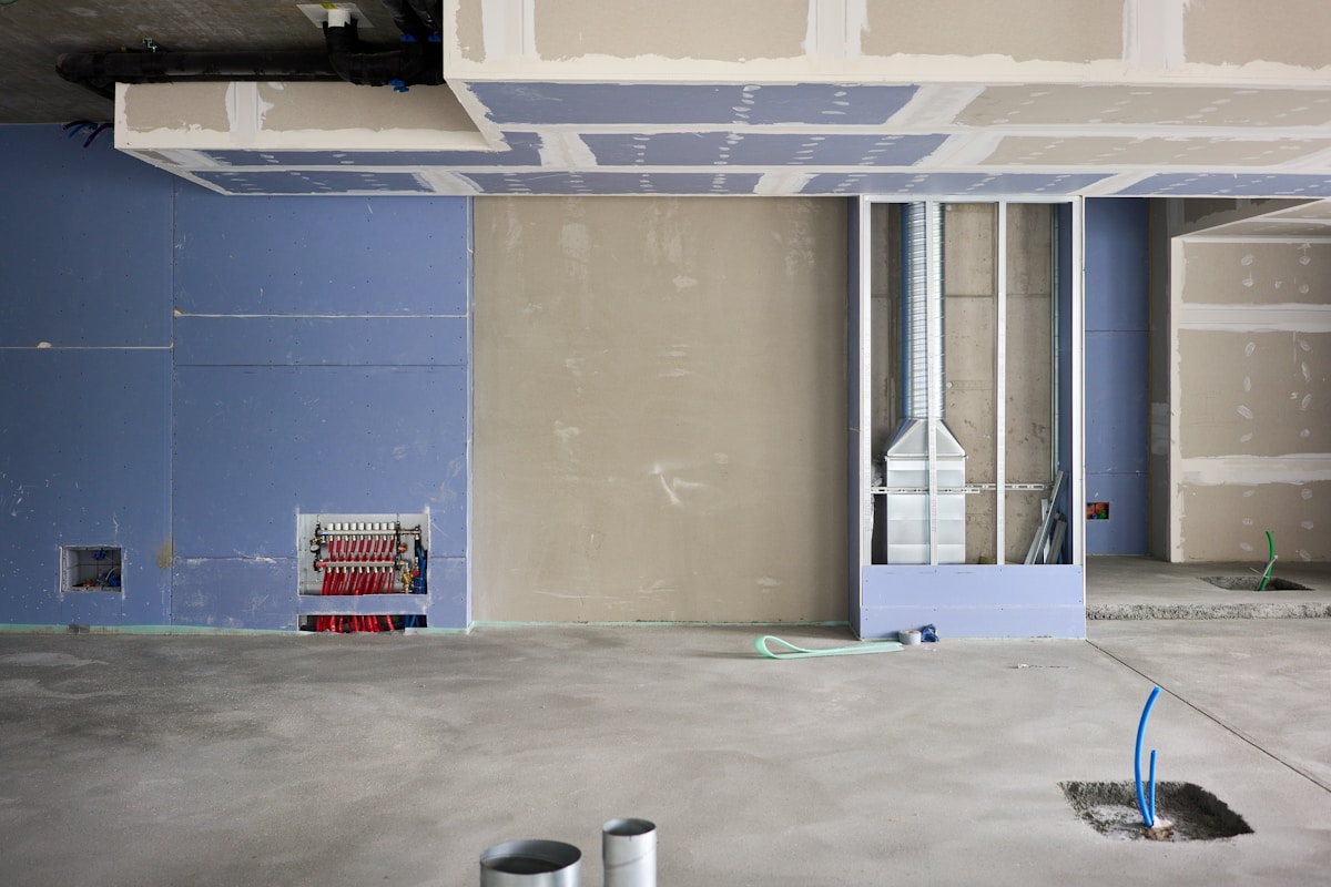 Chantier de construction avec murs en plâtre et équipements électriques.