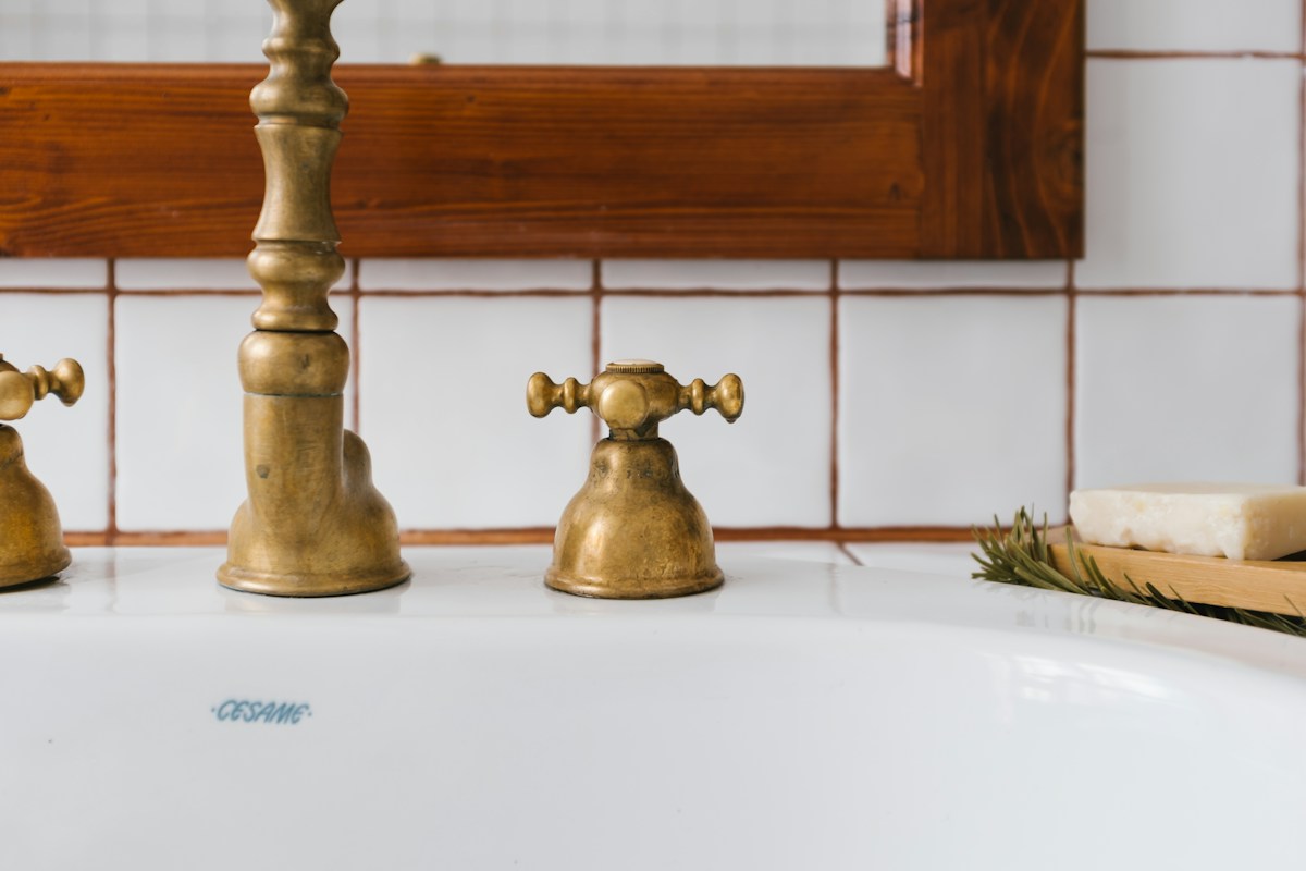Robinetterie en laiton vintage sur lavabo blanc, savon artisanal.